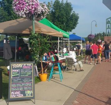 People gather at the whitewater farmers market on a sunny summer day